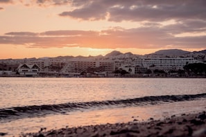 A coastal cityscape with buildings along the waterfront, a clear sky, and a sunset. - 2BR Apt • Balcony • Royal Park by SeaNRent (Eilat)
