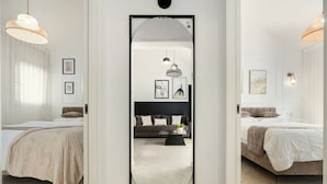 A modern bedroom with a large mirror, two beds, a sofa, and a coffee table. - Bright 2BR Apartment with Balcony at Royal Park (Eilat)