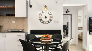 Una cocina moderna con armarios blancos, una mesa redonda con sillas negras y un reloj de pared.