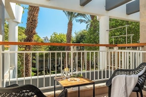 A balcony with a wooden table, two chairs, and a white railing. - 2BR Apt • Balcony • Royal Park by SeaNRent (Eilat)