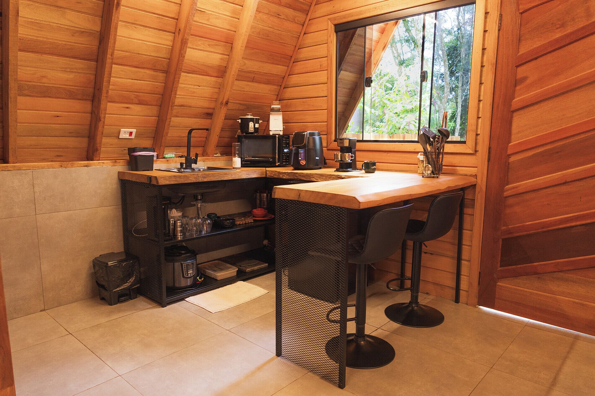 Een gezellige, kleine keuken met houten wanden, een raam en een eethoekje met twee stoelen.