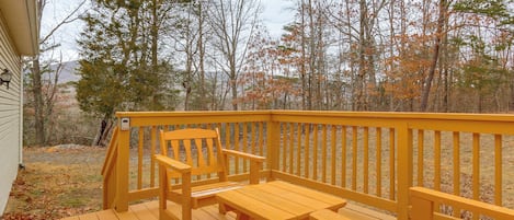 Une terrasse en bois avec une table et des chaises, donnant sur une zone boisée.