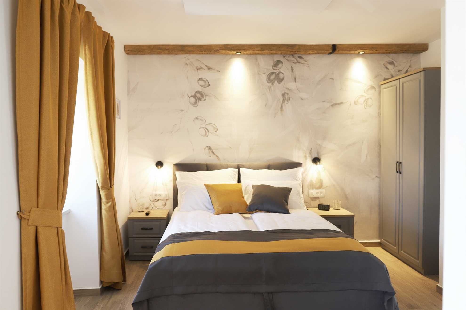 Une chambre à coucher comprenant un lit, des tables de chevet, une armoire et un mur orné d’un motif évoquant le marbre.