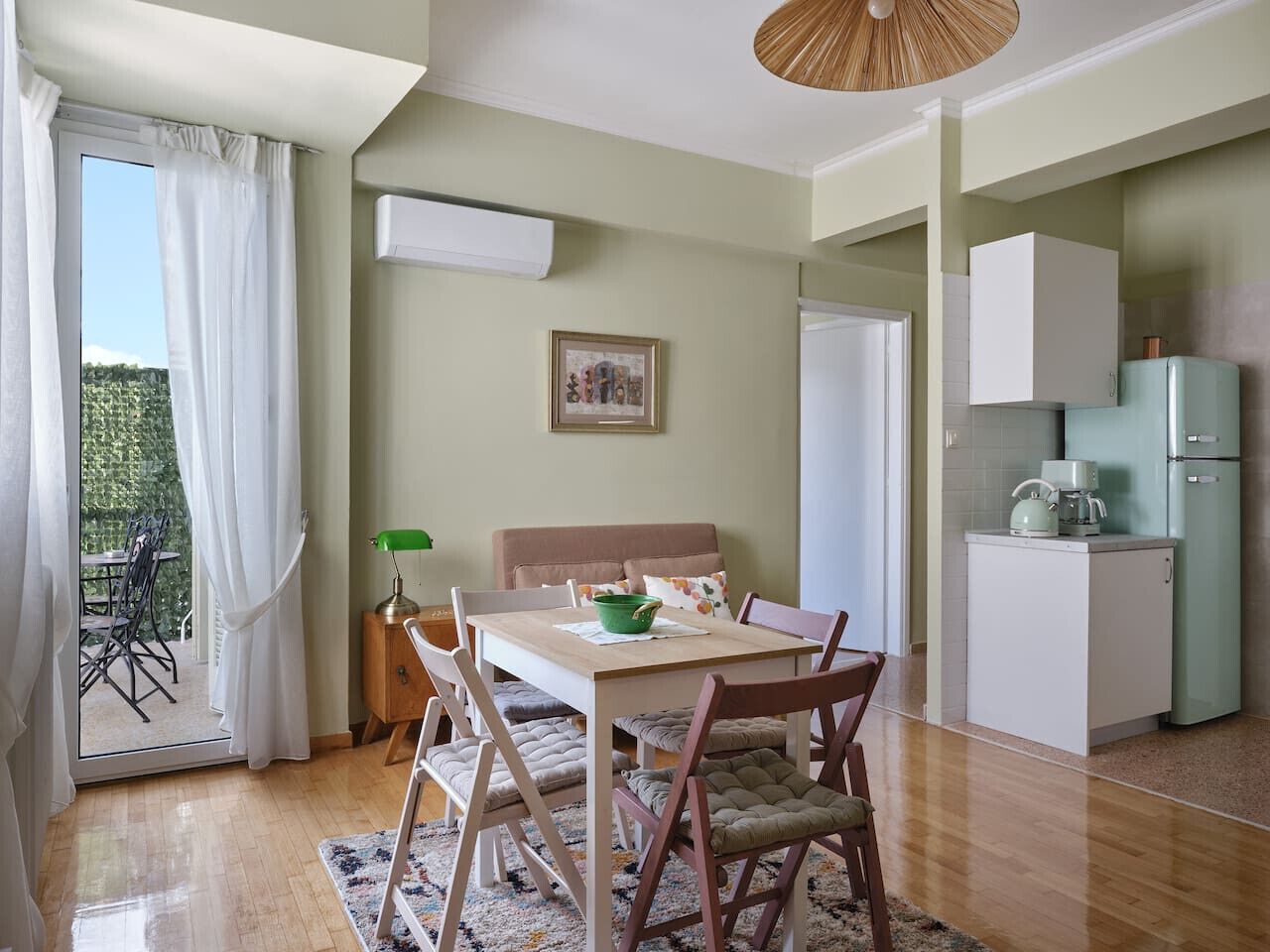 A cozy room with a dining table, chairs, a sofa, and a kitchen area with a refrigerator and cabinets.