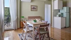 A cozy room with a dining table, chairs, a sofa, and a kitchen area with a refrigerator and cabinets.