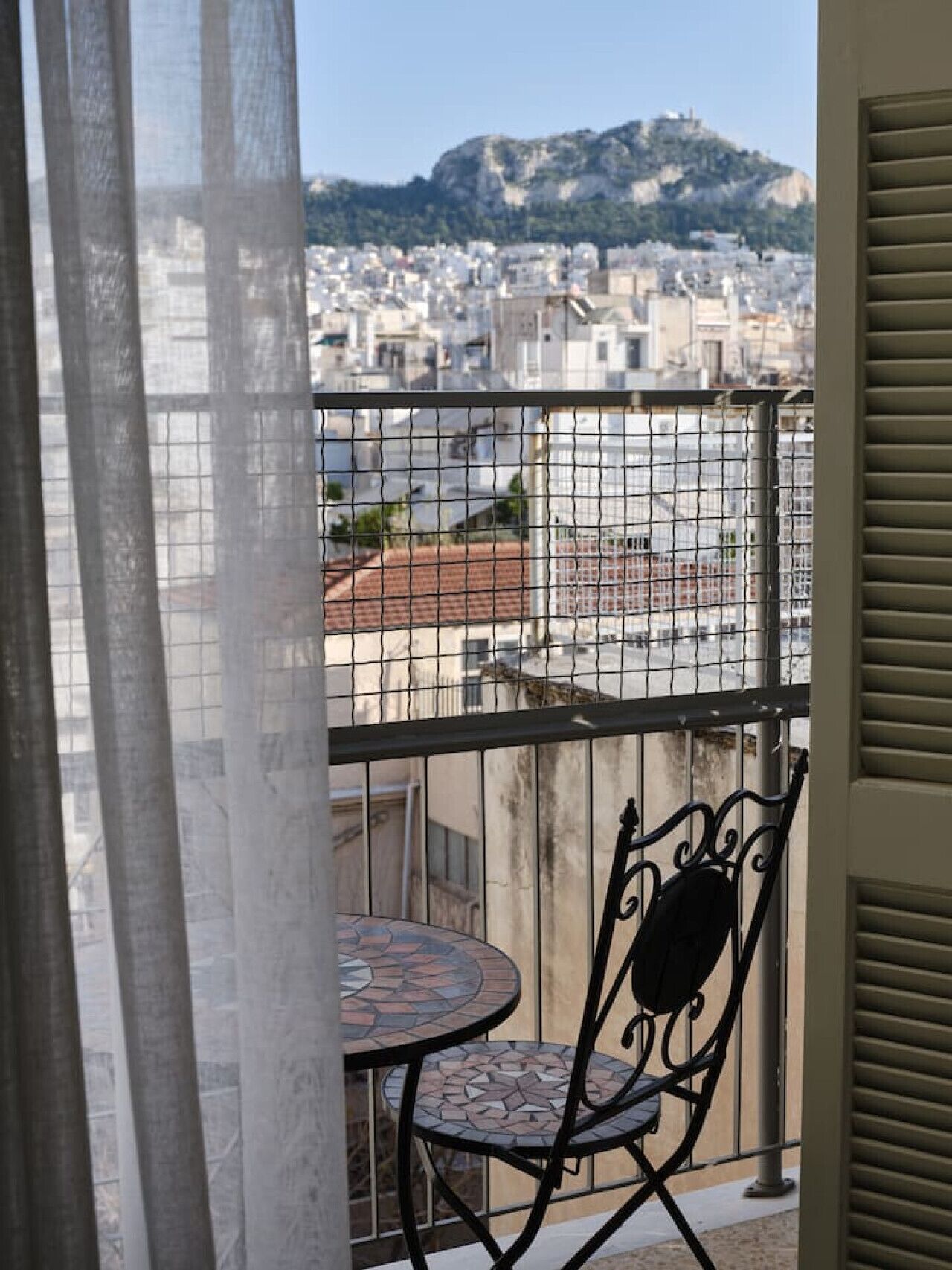 Een balkon met uitzicht op een stadsgezicht en een berg.