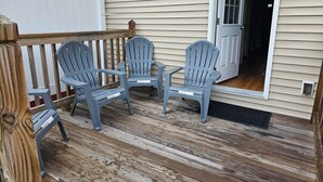 Un terrazzo in legno con tre poltrone Adirondack e un tavolino.
