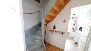 Eine Treppe mit Holzvertäfelung, ein an der Wand befestigtes Regal mit Pflanze und eine Tür zu einem anderen Raum.
