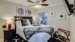 A bedroom with a bed, bedside tables, a ceiling fan, artwork, and a window. - 5BR Hideaway w/ Heated Pool/Hot Tub/Billiards Table (Glendale)