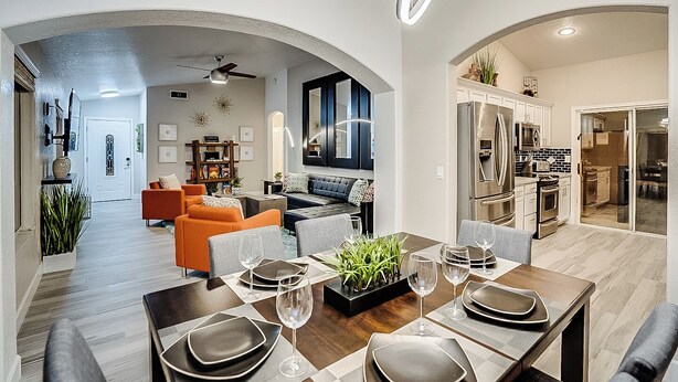 A modern dining area with a wooden table set for four, a kitchen with stainless steel appliances, and an open-plan living space with a sofa and a bookshelf. - 5BR Hideaway w/ Heated Pool/Hot Tub/Billiards Table (Glendale)
