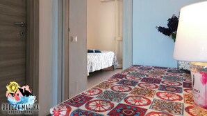 Ein Hotelzimmer mit einem gemusterten Boden, einem Bett mit weißer Bettdecke, einem Nachttisch mit Lampe und einem Bild an der Wand.