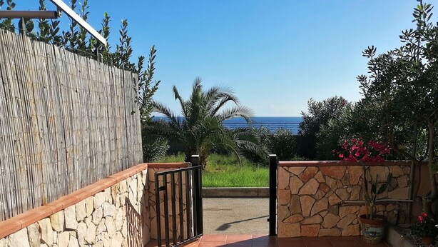 Eine Terrasse mit Tisch für zwei Personen, Blick aufs Meer und eine Steinmauer.