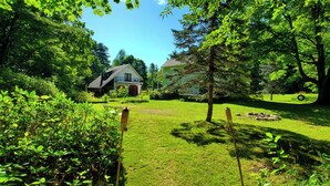Une maison entourée d’une végétation luxuriante et d’arbres.