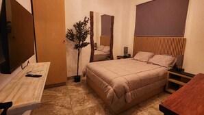 A bedroom with a bed, bedside tables, a mirror, a plant, and a wooden desk. - Apartment in downtown San Jose del Cabo on the transpeninsular highway. (San José del Cabo)