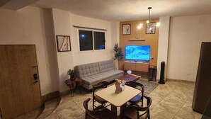 A compact living space with a sofa, dining table, chairs, a TV, and a refrigerator. - Apartment in downtown San Jose del Cabo on the transpeninsular highway. (San José del Cabo)