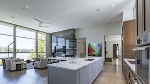 Una cocina moderna con una isla grande, electrodomésticos integrados y vistas al exterior.