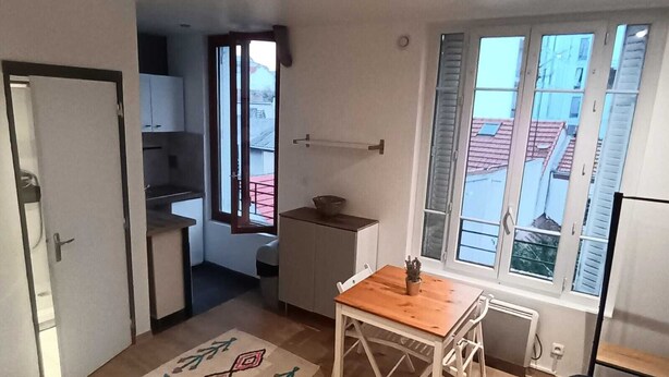 A compact living space with a dining area, kitchenette, and a view through a window.