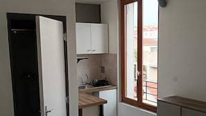 A compact kitchen with a window, a sink, and cabinets.