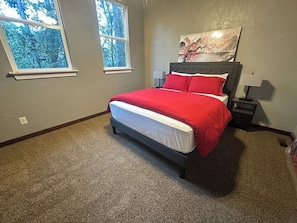 A bedroom with a bed, two windows, a nightstand, and a wall-mounted lamp. - Downtown | Pet Friendly | Cabin 3 (Tallahassee)