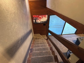 A wooden staircase with a handrail, carpeted steps, and a view of the outdoors through a window. - Downtown | Pet Friendly | Cabin 3 (Tallahassee)