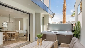 A modern outdoor living area with a hot tub, wicker furniture, and a view of the city. - Sunstone Retreat: Hot Tub + Desert Color Lagoon + Beaches, Hot Tub (St. George)
