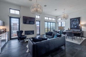 A spacious living area with a black leather sofa, a fireplace, and a dining table with chairs. There are large windows providing natural light and a view of the city. - 121 Hotel Buyout by Avantstay Buyout of 121 Hotel w/ Living Areas & Meeting Room! Sleeps 58 (Nashville)