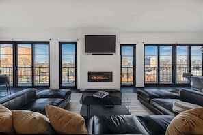 A modern living room with a fireplace, black leather sofas, a glass coffee table, and large windows offering city views. - 121 Hotel Buyout by Avantstay Buyout of 121 Hotel w/ Living Areas & Meeting Room! Sleeps 58 (Nashville)