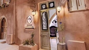 A building with a warm facade, a welcoming entrance with a sign, and decorative plants. - Madame Hortense Hotel (Chania)