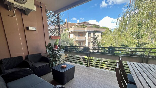 Un balcone con mobili in vimini, un tavolo e piante in vaso.