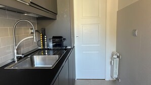 Una cucina moderna con elettrodomestici in acciaio inossidabile, un lavello doppio e una porta bianca.