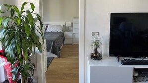 Una camera d'albergo con un letto, una televisione, una pianta e un vaso decorativo.