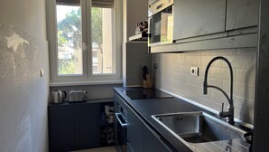 Una cucina compatta con finestra, microonde integrato ed elettrodomestici in acciaio inossidabile.