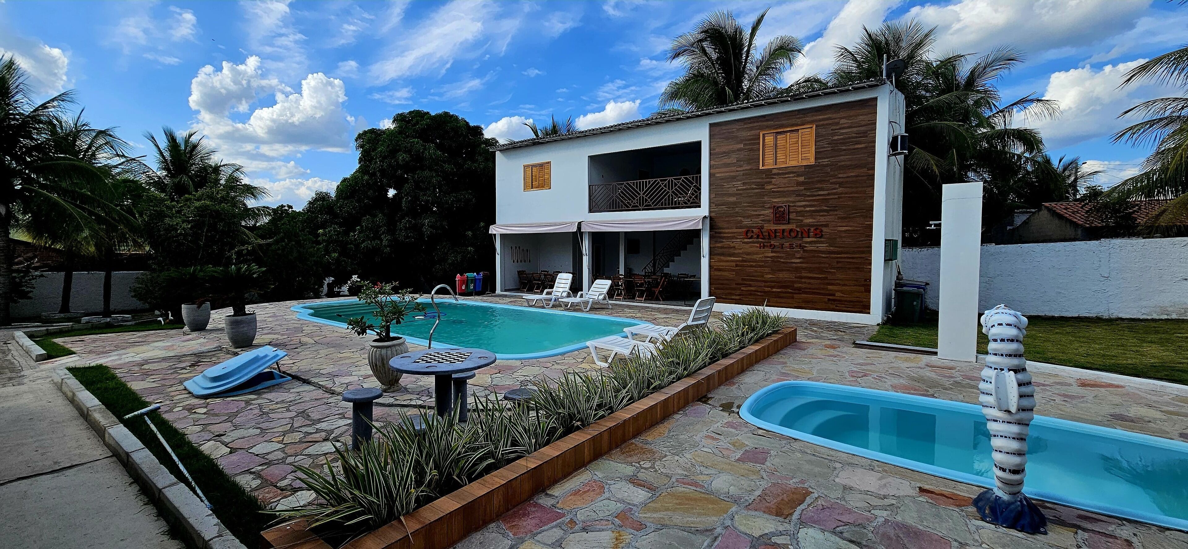 A hotel with a pool area, including lounge chairs and a small table.