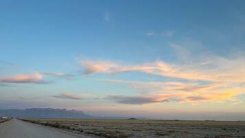 A long, straight road in a flat, open landscape with distant mountains under a clear sky.