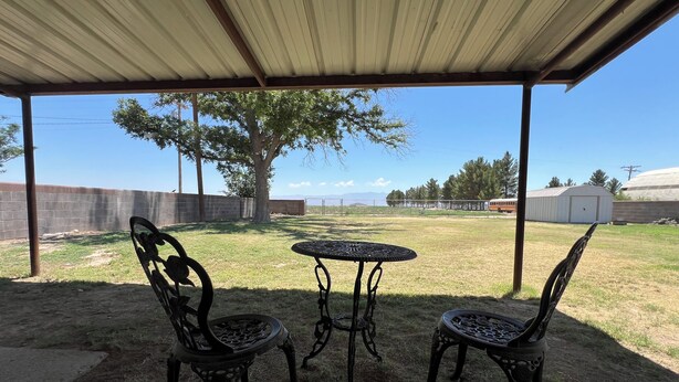 Un espacio de patio cubierto con dos sillas de metal ornamentadas y una mesa.