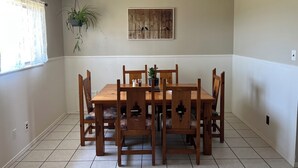 Un comedor con una mesa y sillas de madera, una planta en maceta y una obra de arte colgada en la pared.