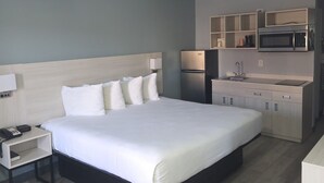 Una camera d'albergo con un letto grande, un comodino con il telefono, un piccolo armadietto, un forno a microonde e un lavandino.