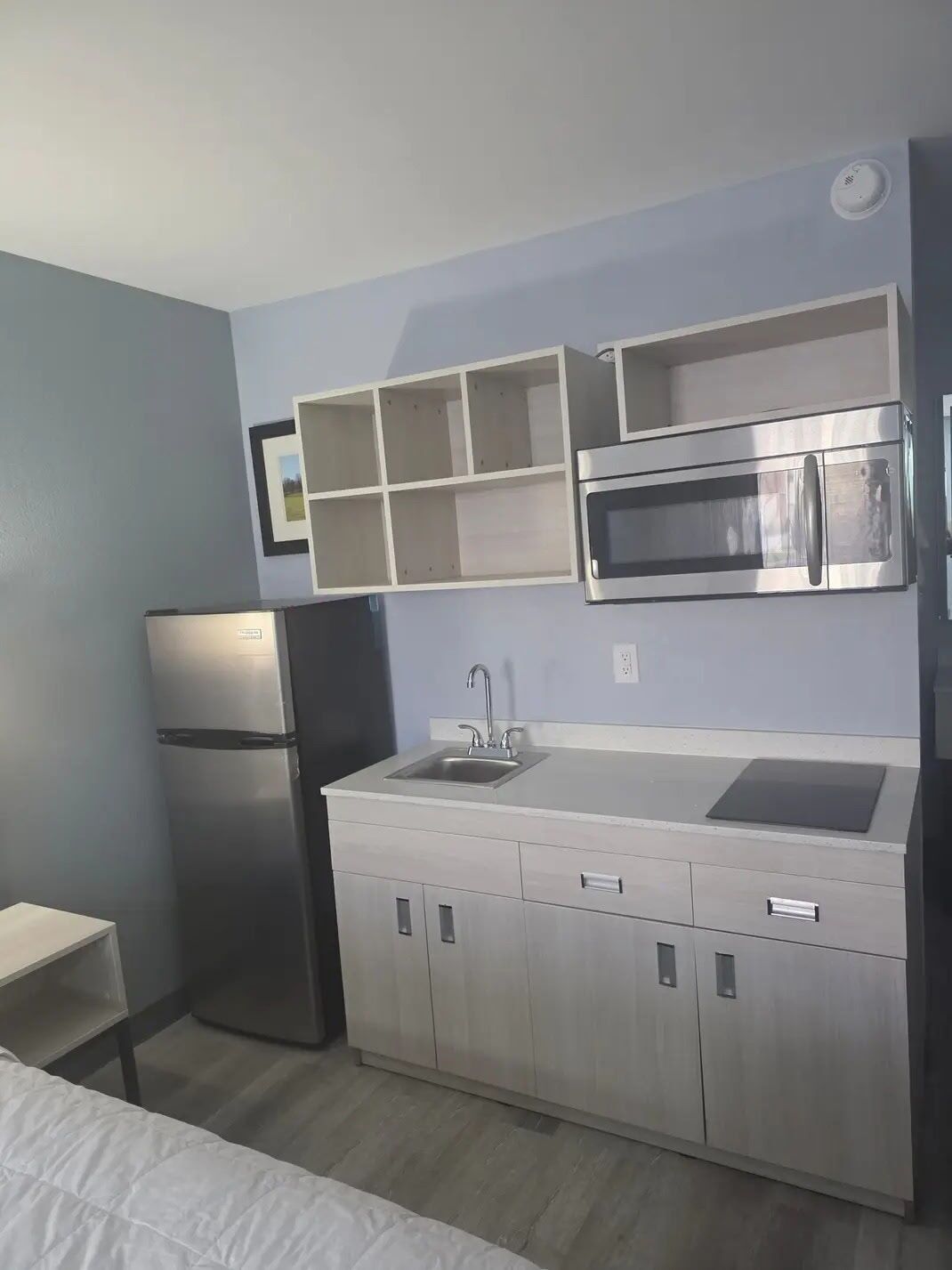 A compact kitchen with a built-in microwave, stainless steel refrigerator, and a sink.