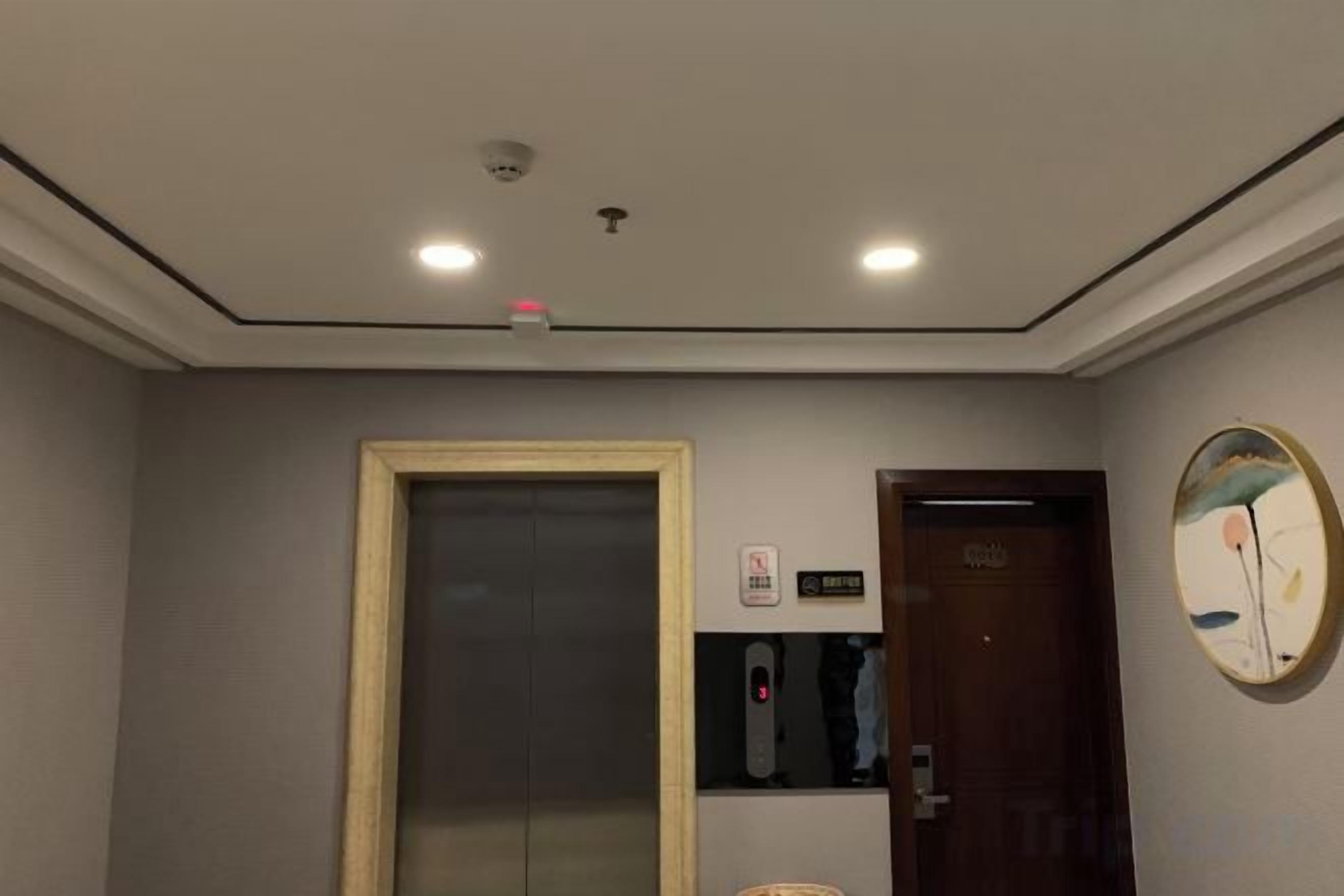 Una habitación de hotel con una puerta, un ascensor y un cartel en la pared.