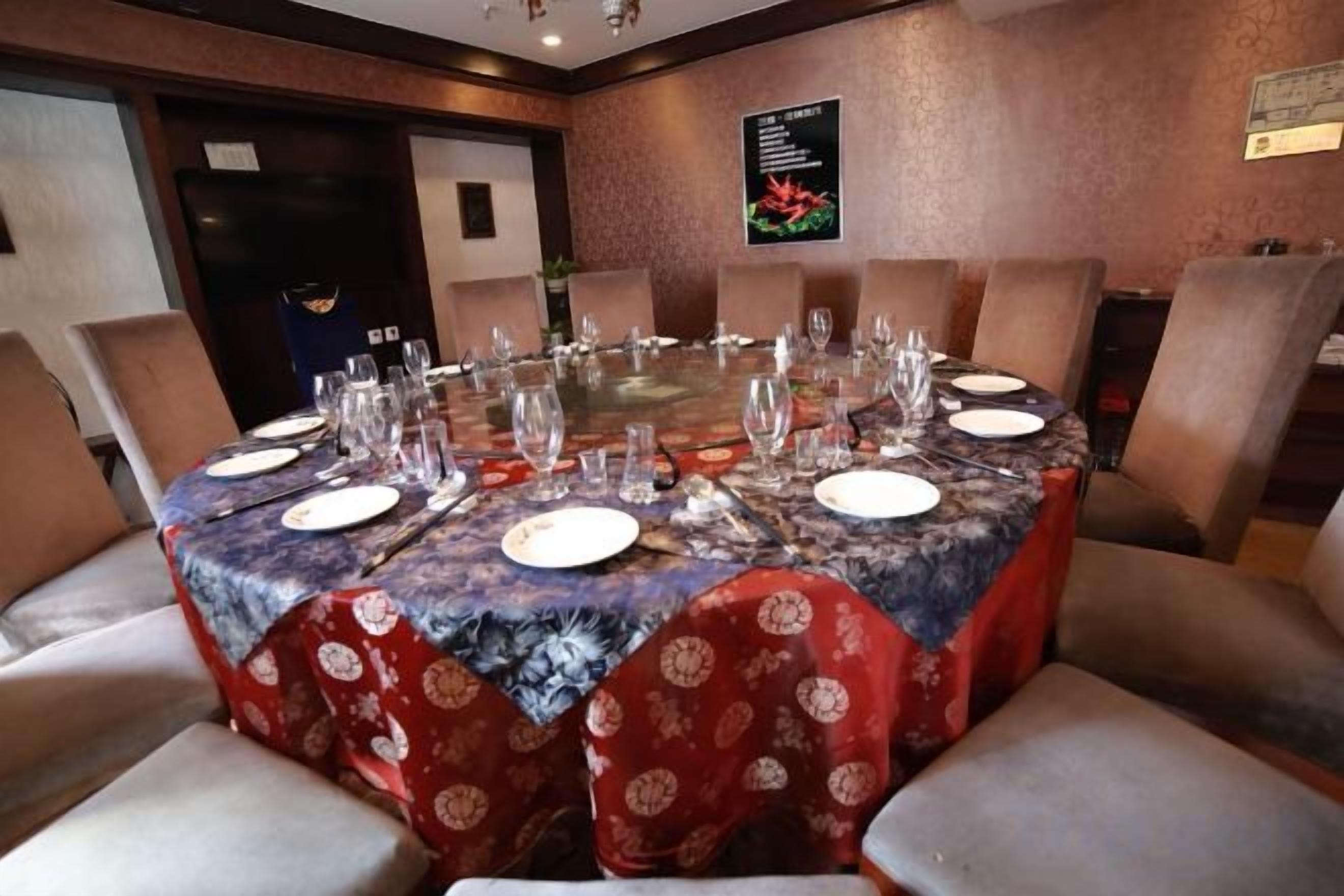 A conference room with a round table set for a meeting, surrounded by chairs.