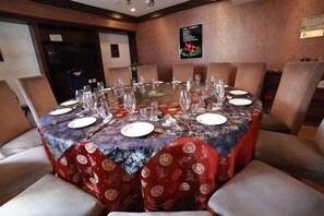 A conference room with a round table set for a meeting, surrounded by chairs.