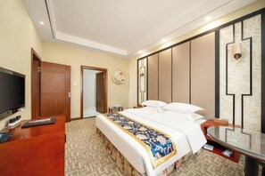 Una habitación de hotel con cama, mesita de noche, televisor, escritorio y espejo.