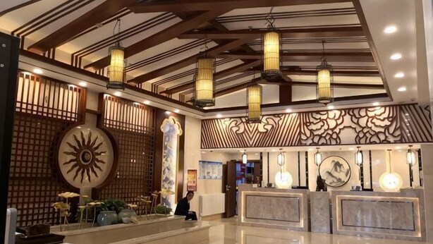 Un hall d’hôtel comprenant un comptoir d’accueil, des panneaux muraux décoratifs et des lanternes suspendues.