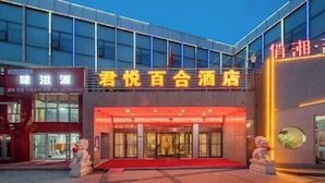L’entrée d’un hôtel, avec un tapis rouge, des portes en verre et deux statues de chaque côté.