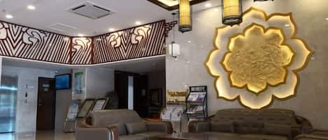 Un vestíbulo con mostrador de recepción, zona de estar y una gran pared decorativa.