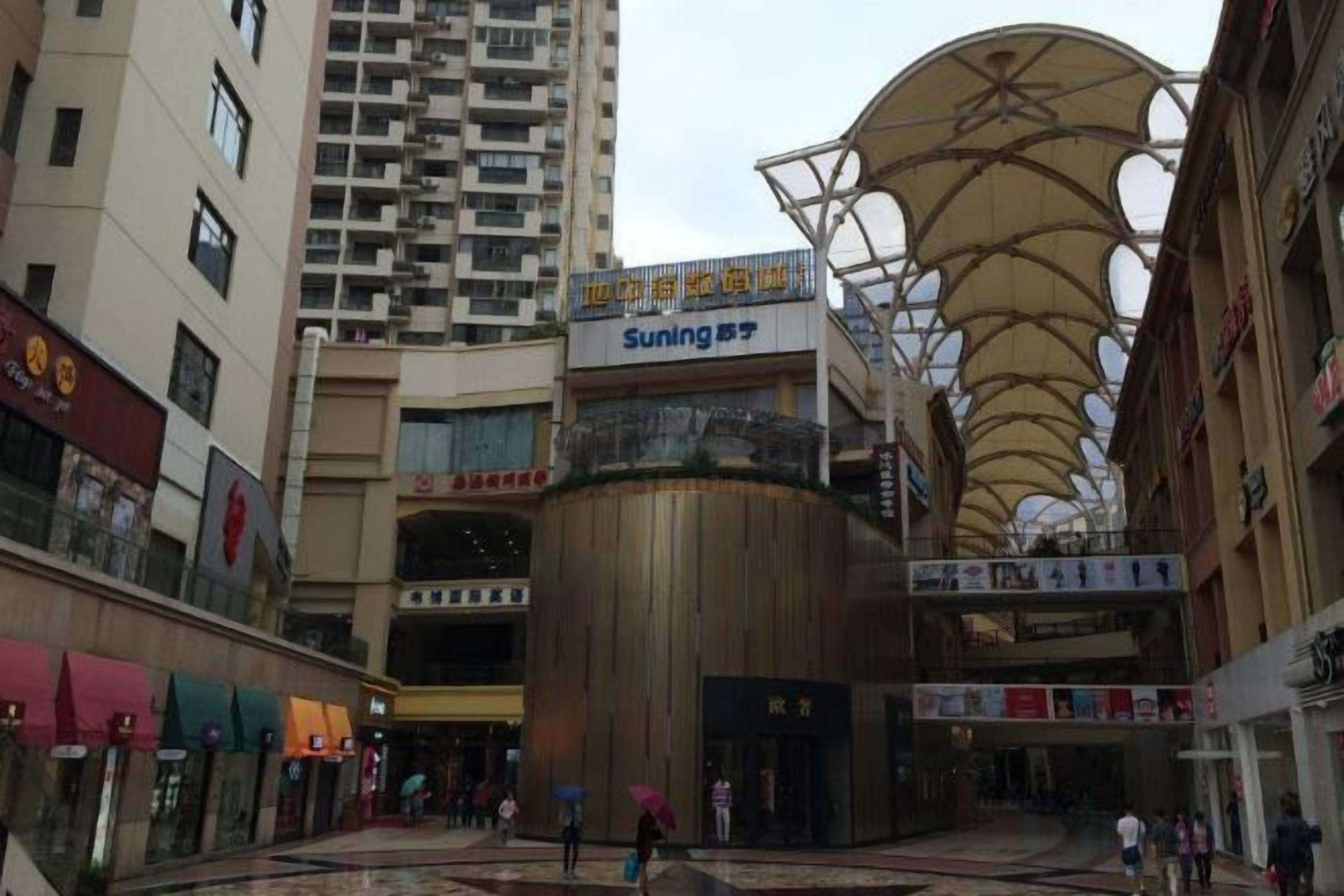 Un centre commercial à plusieurs niveaux, doté d’un atrium central, de divers magasins et d’une grande structure de plafond incurvée.