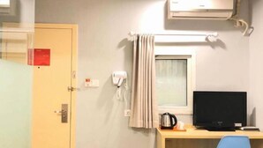 A hotel room with a desk, a television, a kettle, a window with curtains, an air conditioner, and a door with a sign. - 99 Inn (Shanghai Songjiang University Town) (Shanghai)