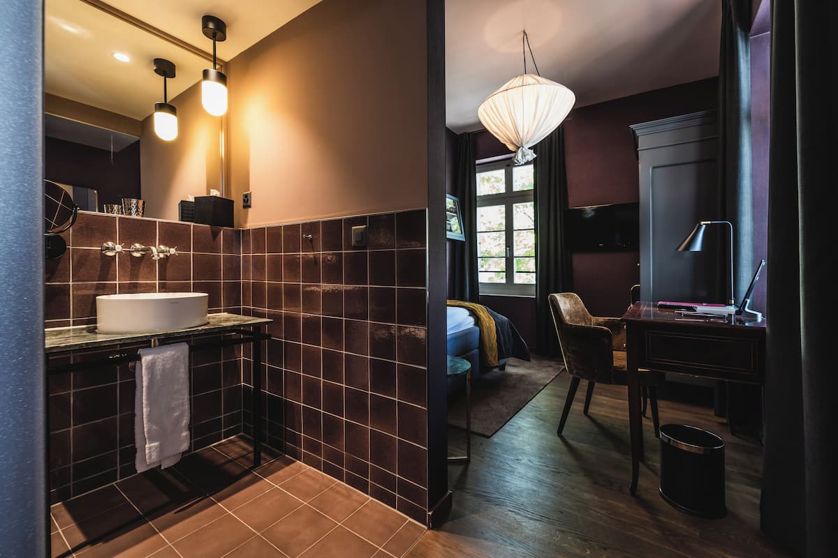 Ein modernes Badezimmer mit einem großen Waschbecken, dunklen Fliesen und Holzboden.