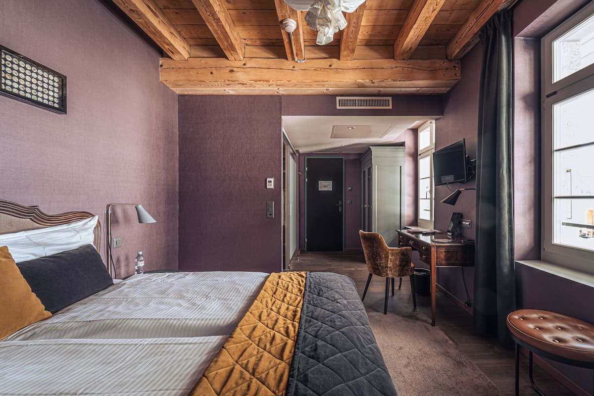 Ein Hotelzimmer mit Bett, Schreibtisch, Stuhl und Fernseher.