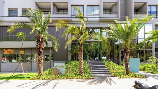 A modern building with multiple balconies, palm trees, and a signboard. - Charlie Bothanic Campo Belo  (São Paulo)
